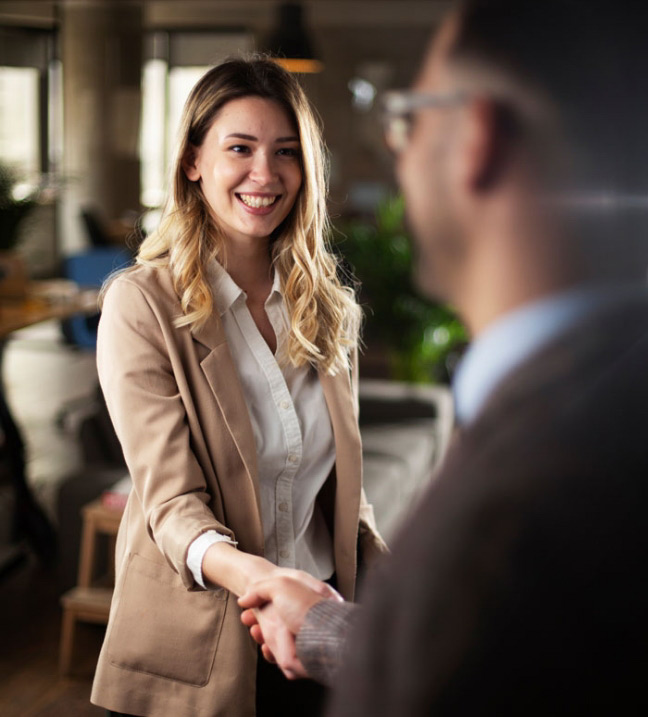 Professional business woman shaking hands with a gentleman in a clean office.