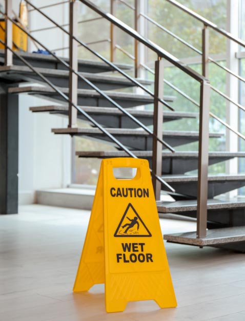 Freshly cleaned building floor with yellow caution sign.