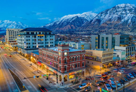 Commercial buildings in downtown Provo, UT with snowy mountains in background.